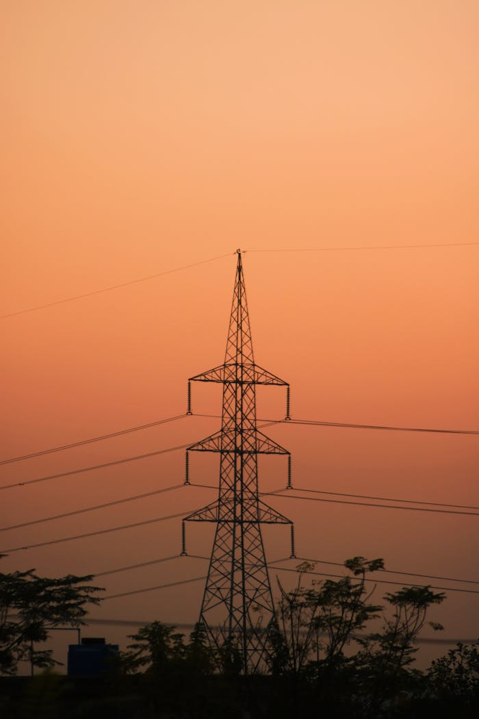 Silhouette of a transmission tower against a vibrant sunset sky in Pakistan.